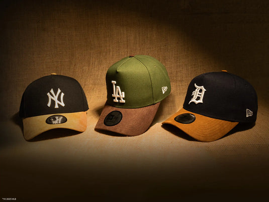 Three baseball caps with different team logos on a brown background