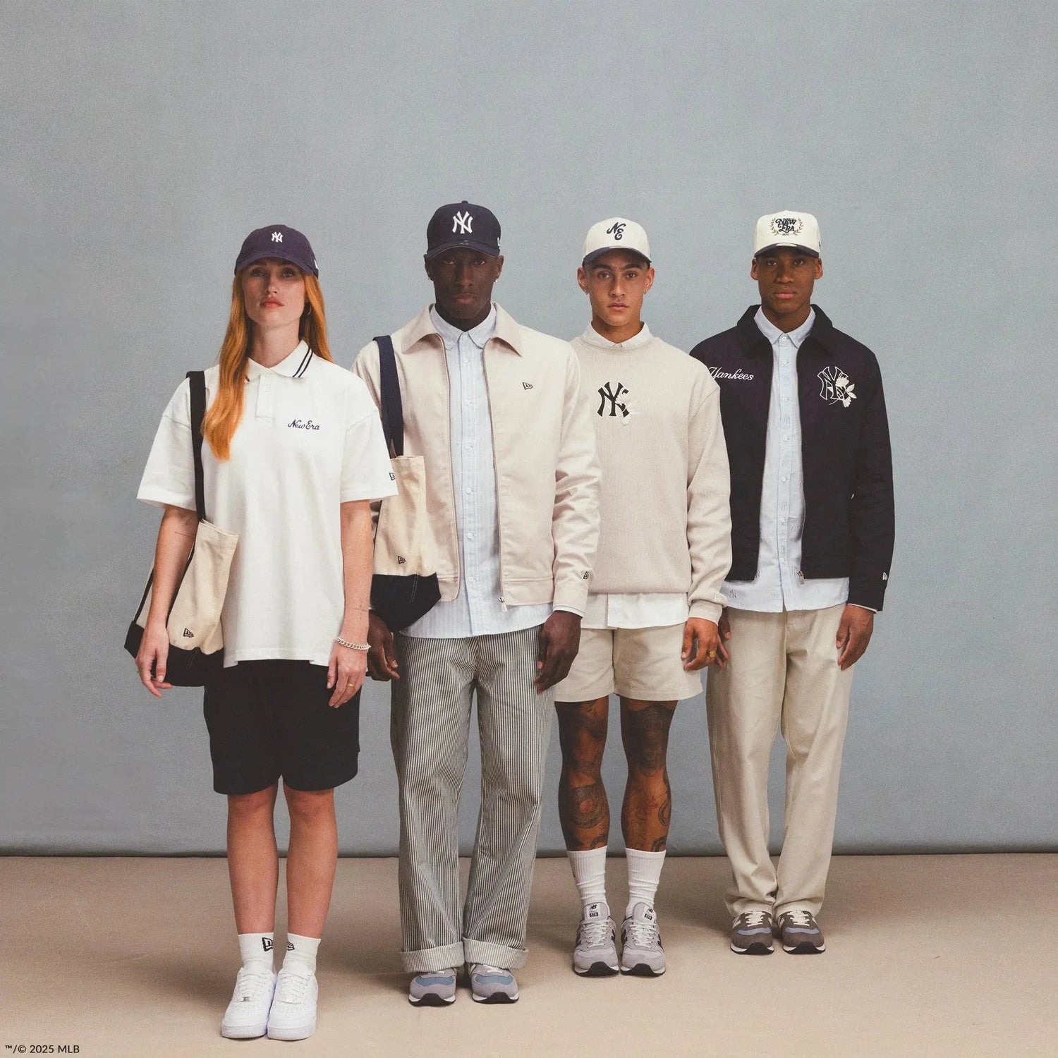 Four models in neutral-toned outfits and New York Yankees caps stand side by side against a plain backdrop.