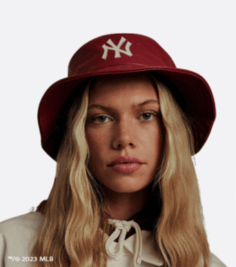 A woman with long hair wearing a red New Era bucket hat 