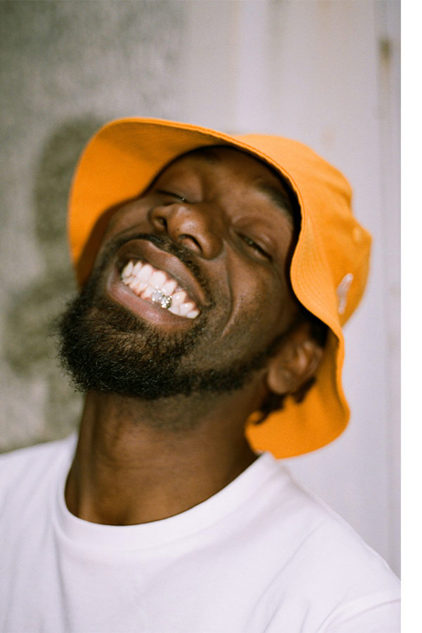 French rapper, Tedax Max, wearing a New Era bucket hat and smiling