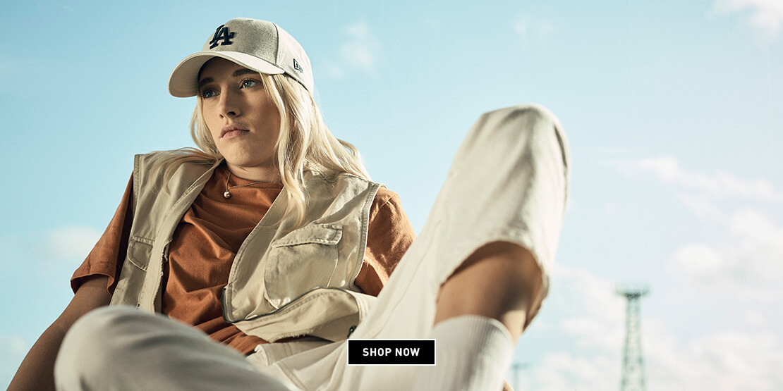 Woman sat in front of a window wearing a stone coloured jersey material LA Dodgers baseball hat